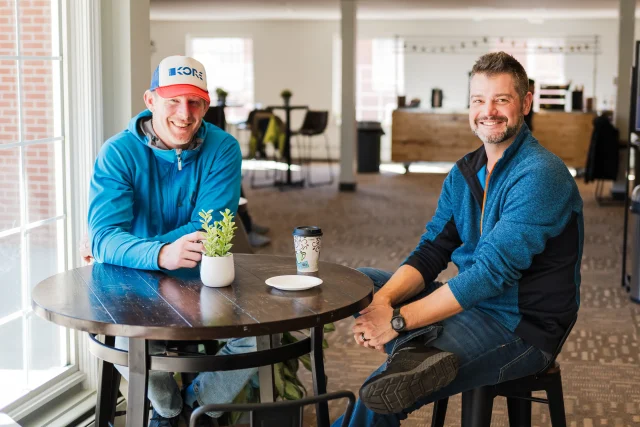 Two men sitting with coffee at a table in the Arvada Vineyard lobby